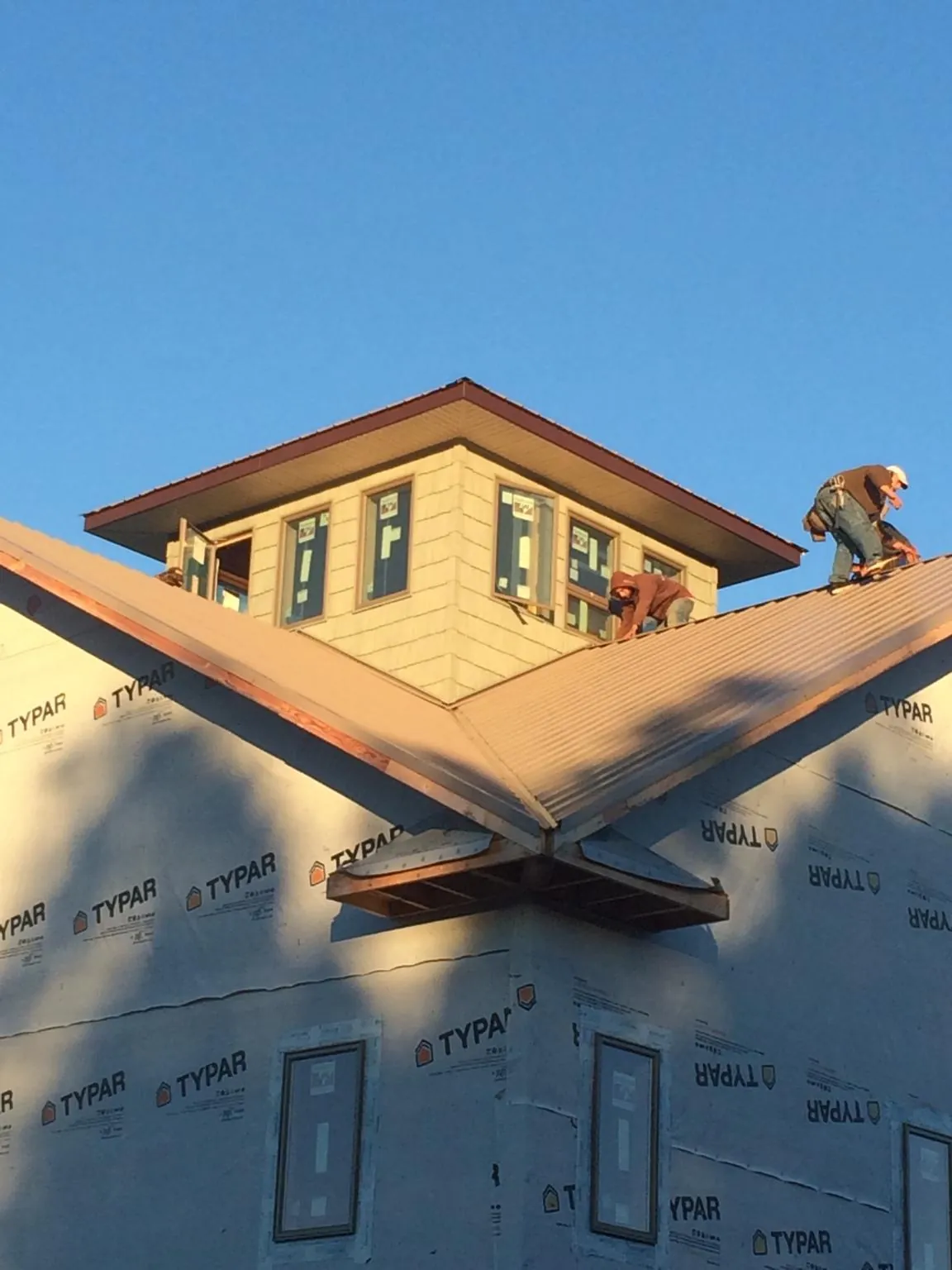 Roofers working around a rooftop cupola on a new metal roof at sunset — Roof Waterproofing in Maricopa by Roofing Brothers